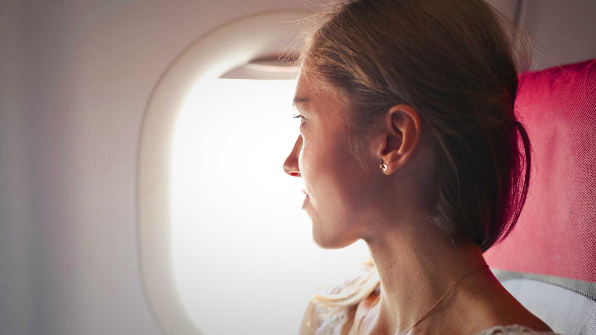 Young woman gazing out airplane window