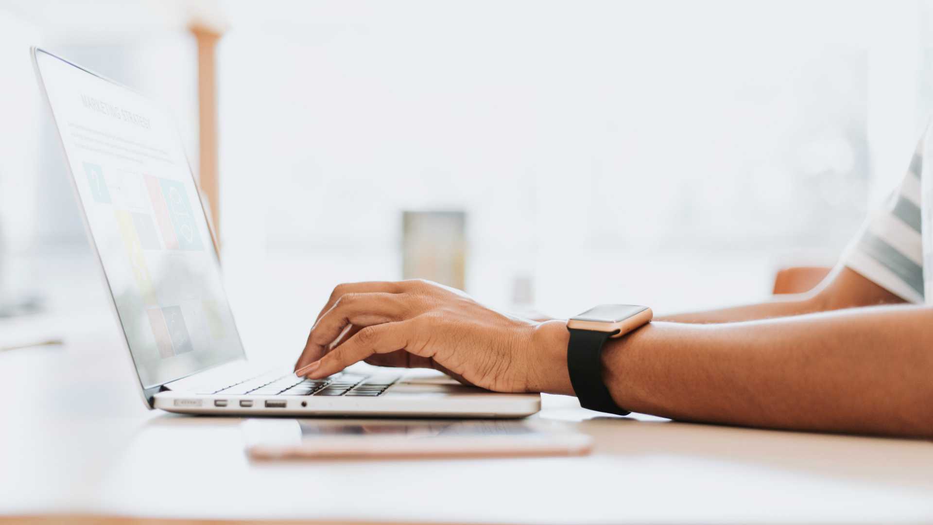 Businessman wearing watch working on laptop at tidy brightly-lit desk