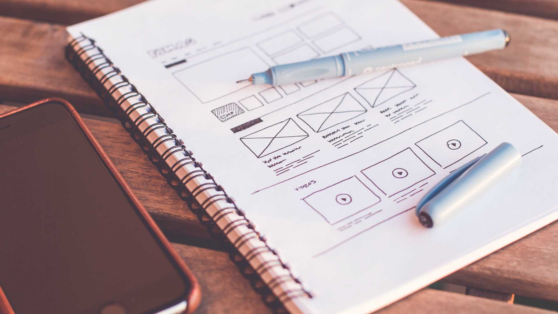 Open notebook filled with storyboarding next to phone on wooden table