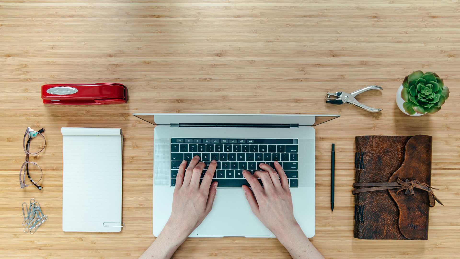 Organized desk with businessperson working on laptop from aerial view