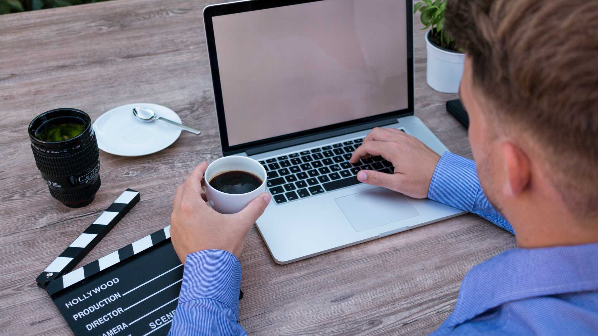 Businessman holding coffee and working on laptop at desk