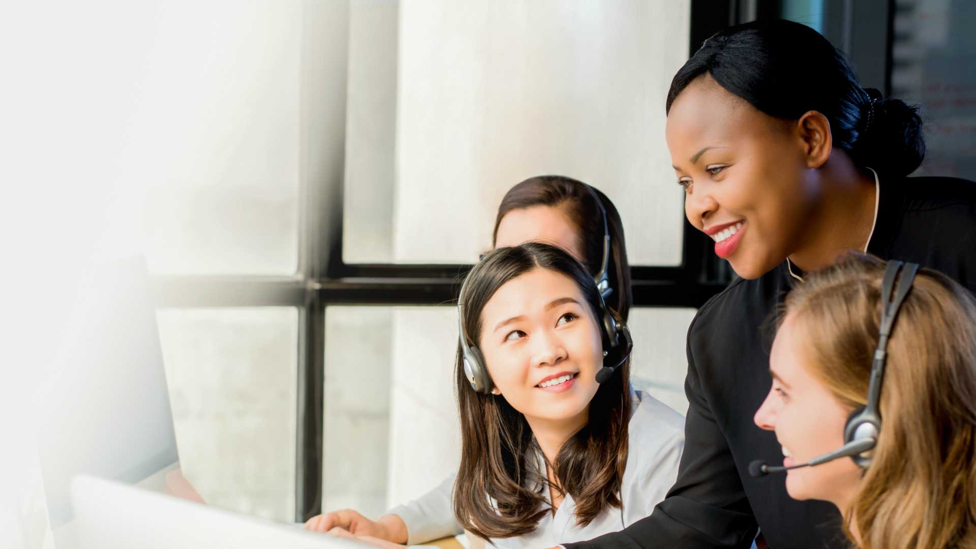 Friendly black businesswoman supervisor training work to her multiethnic colleagues in call center office