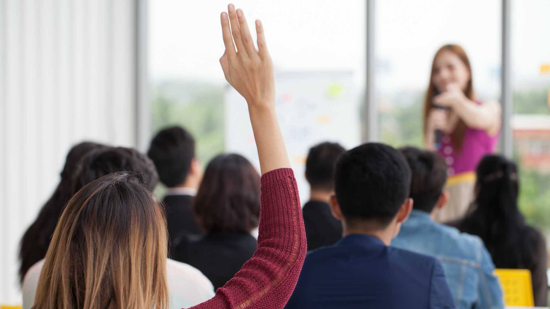 young businesswoman raising hand to question from Speaker in Seminar Group Meeting