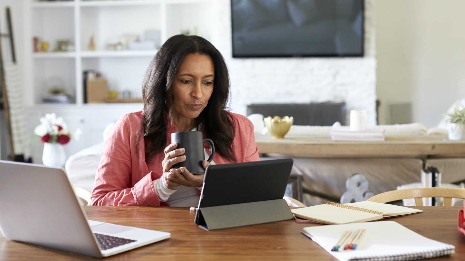 Businesswoman drinking coffee and working on tablet from home