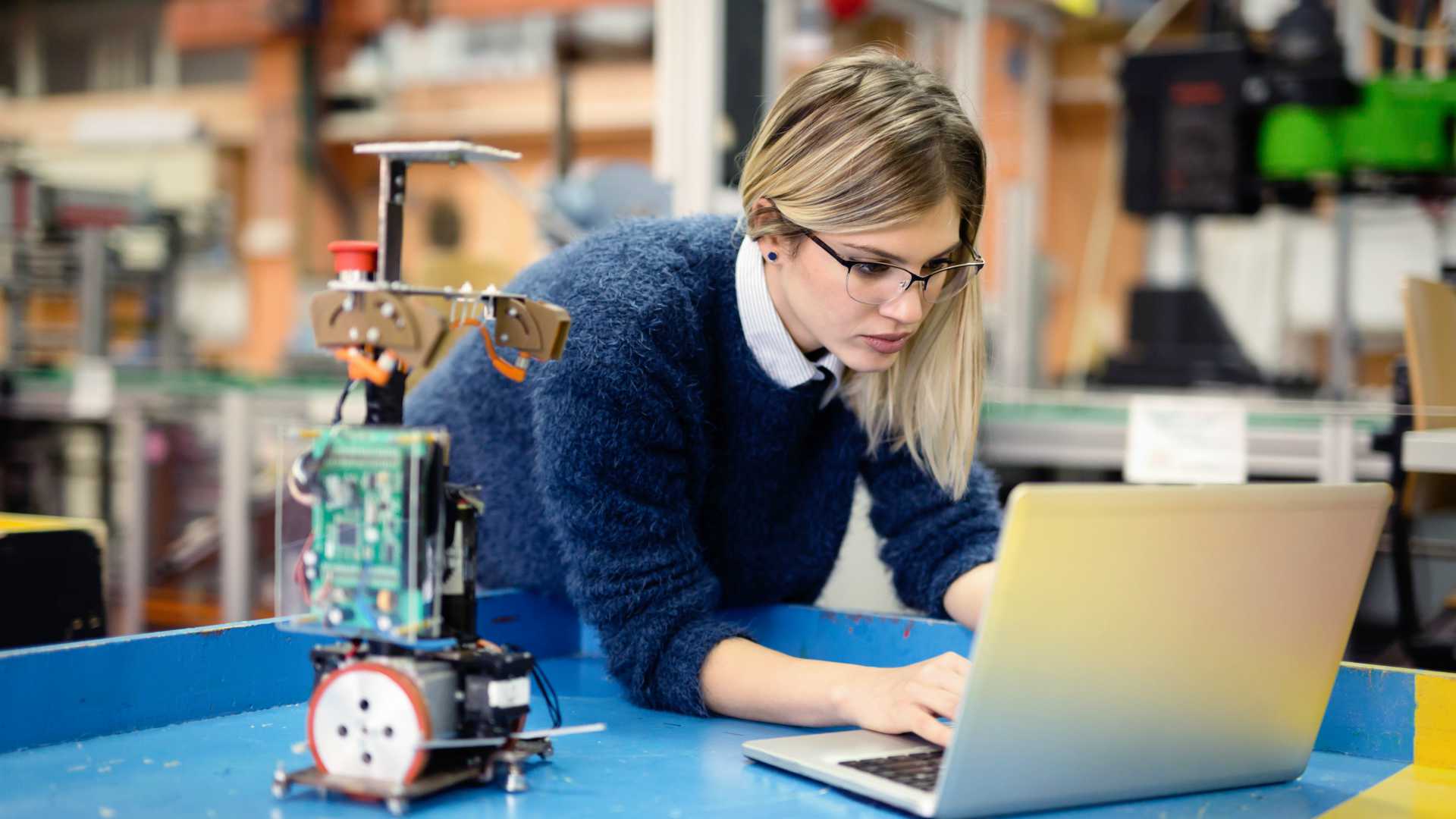 Young woman engineer working on robotics project using laptop