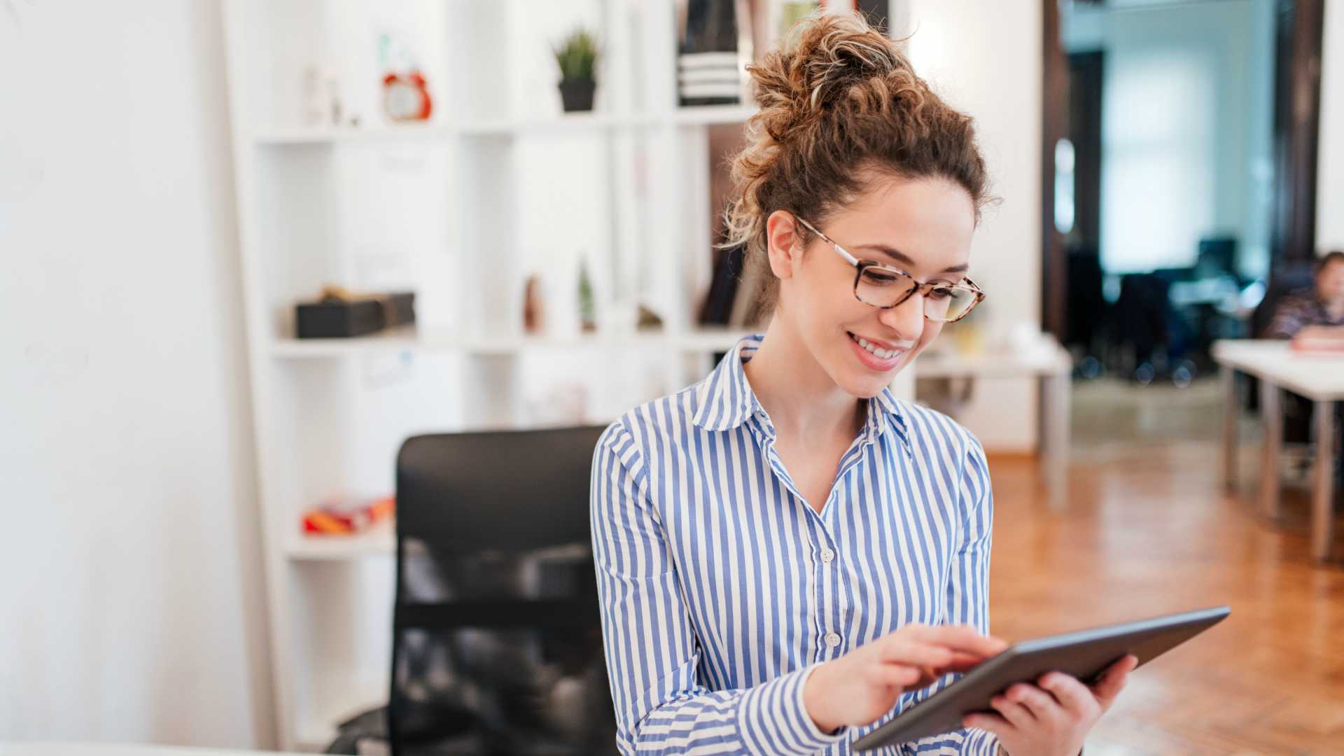 Smiling young businesswoman using digital tablet.