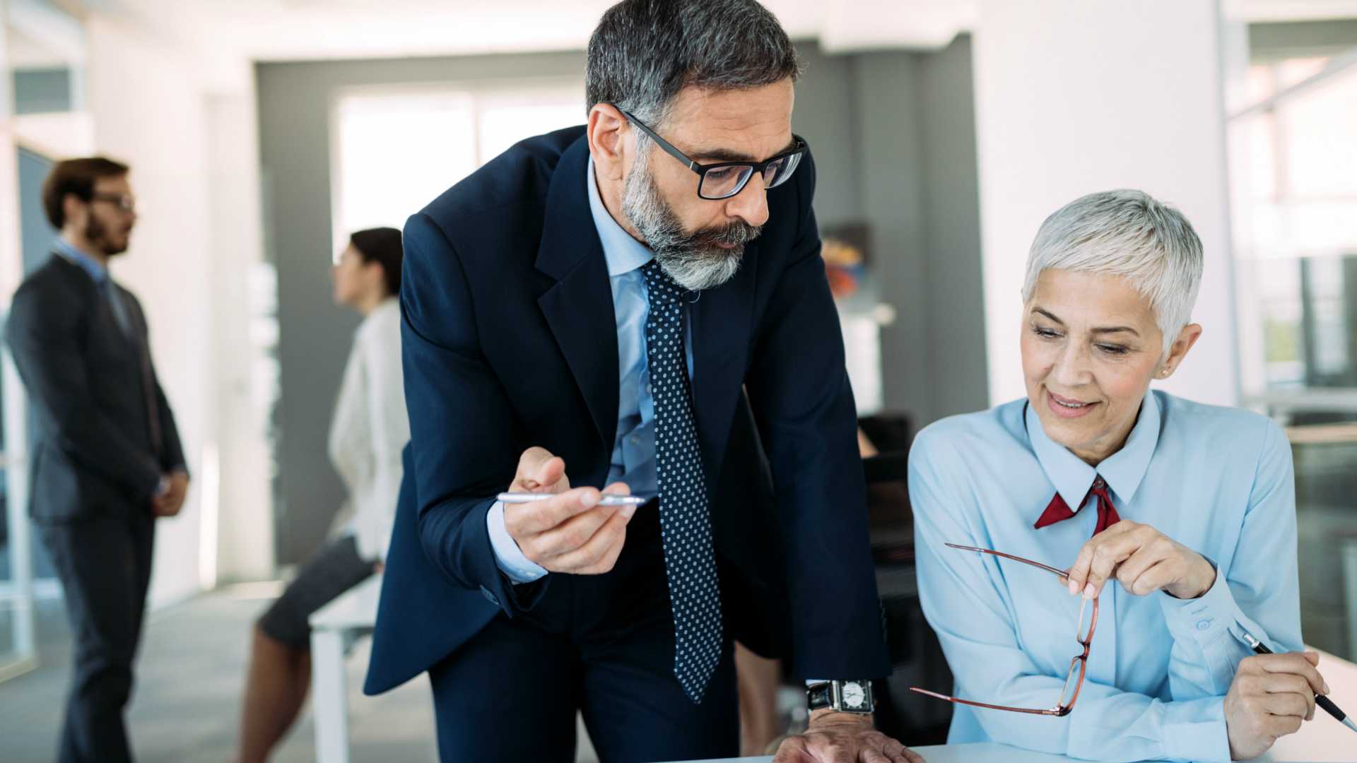 Happy mature businessman and businesswoman planning in modern office