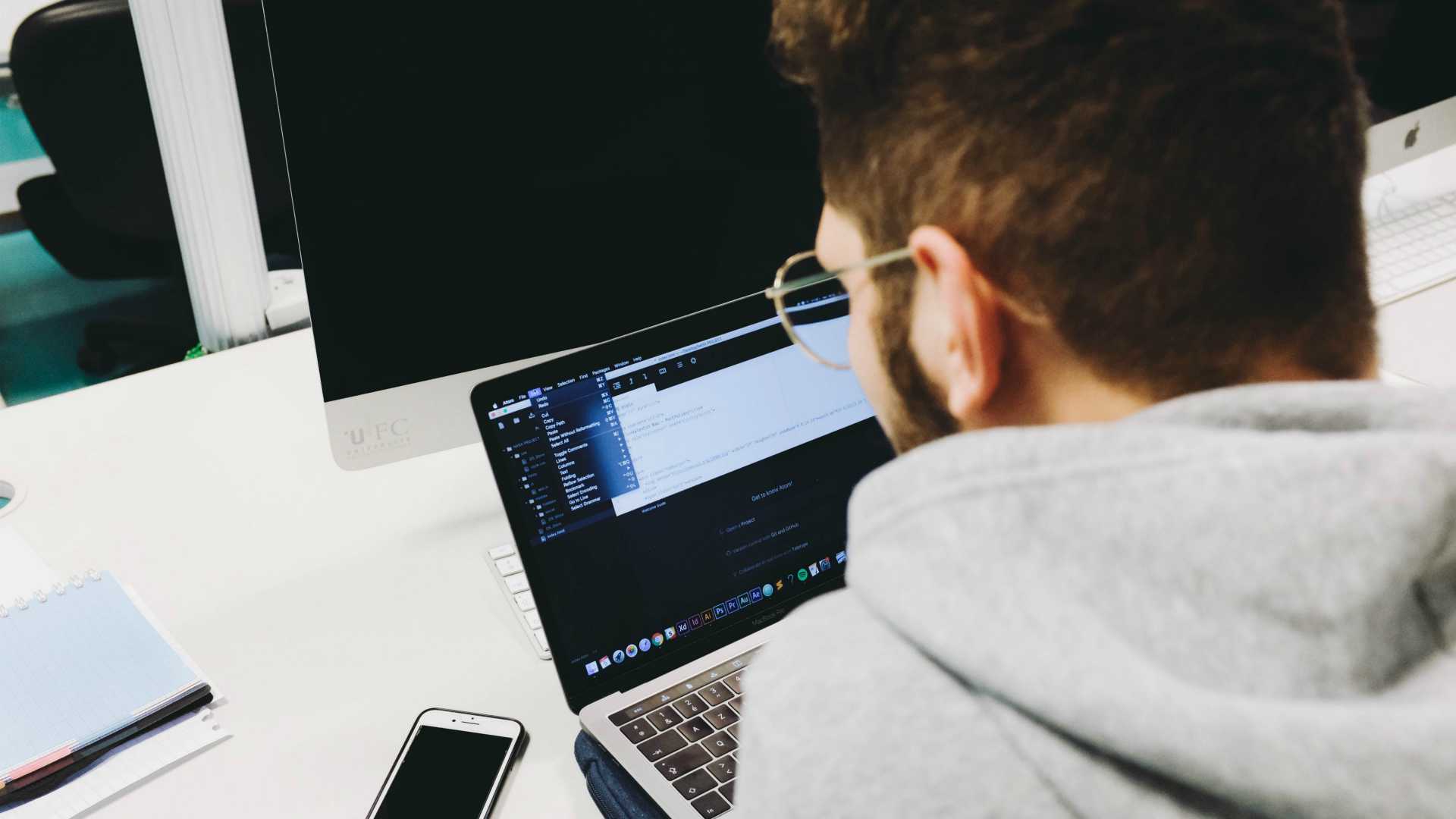Young tech professional working on laptop, image shot over the young man'