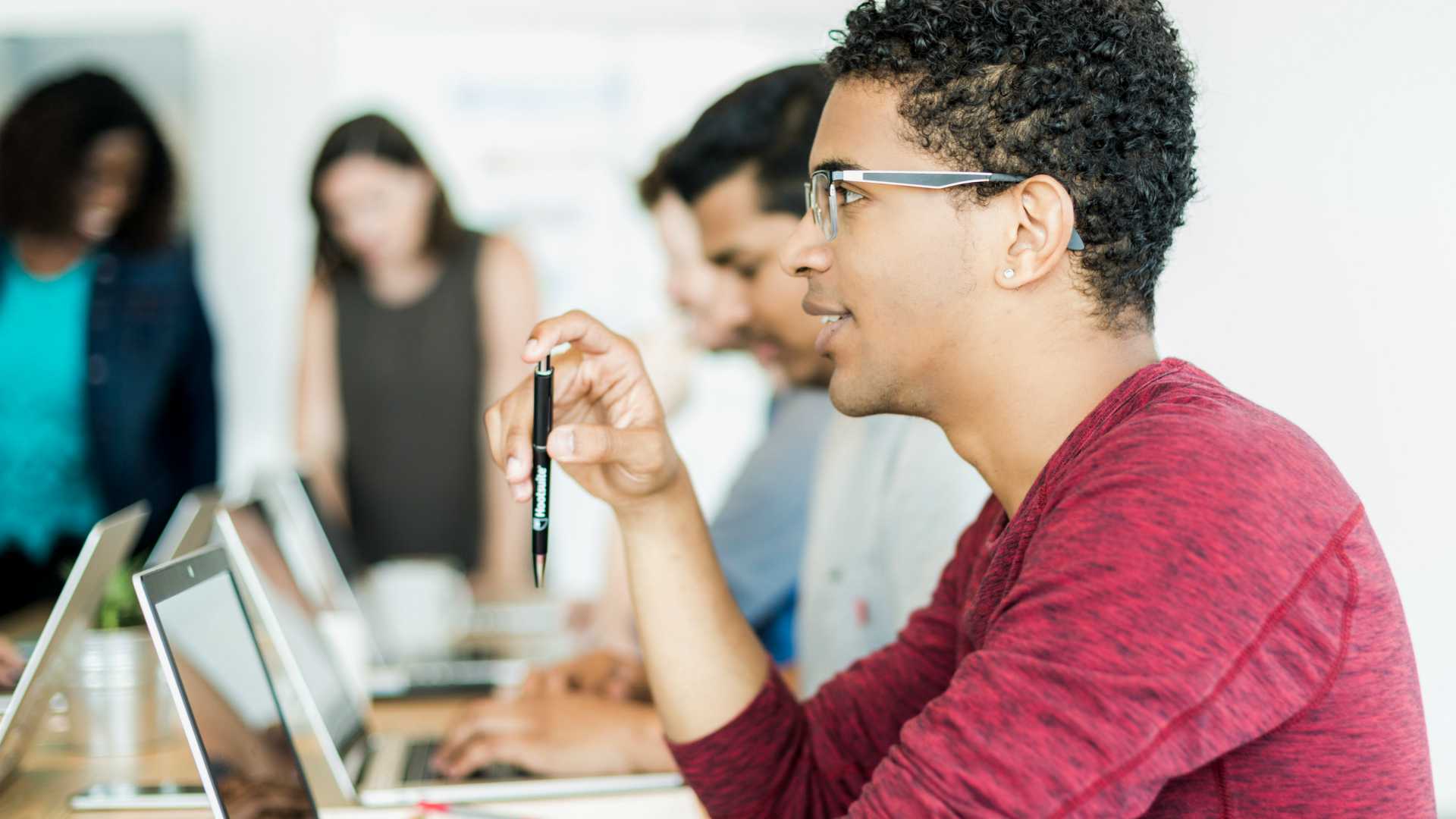 Young African American businessman at table with other colleagues all participating in corporate training