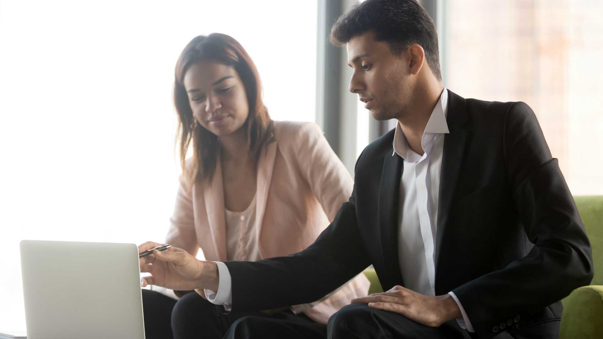 Diverse executive coworkers discuss online project work together