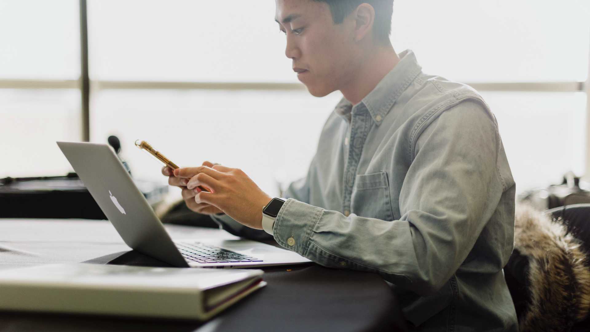 Young businessman on smartphone while sitting at laptop