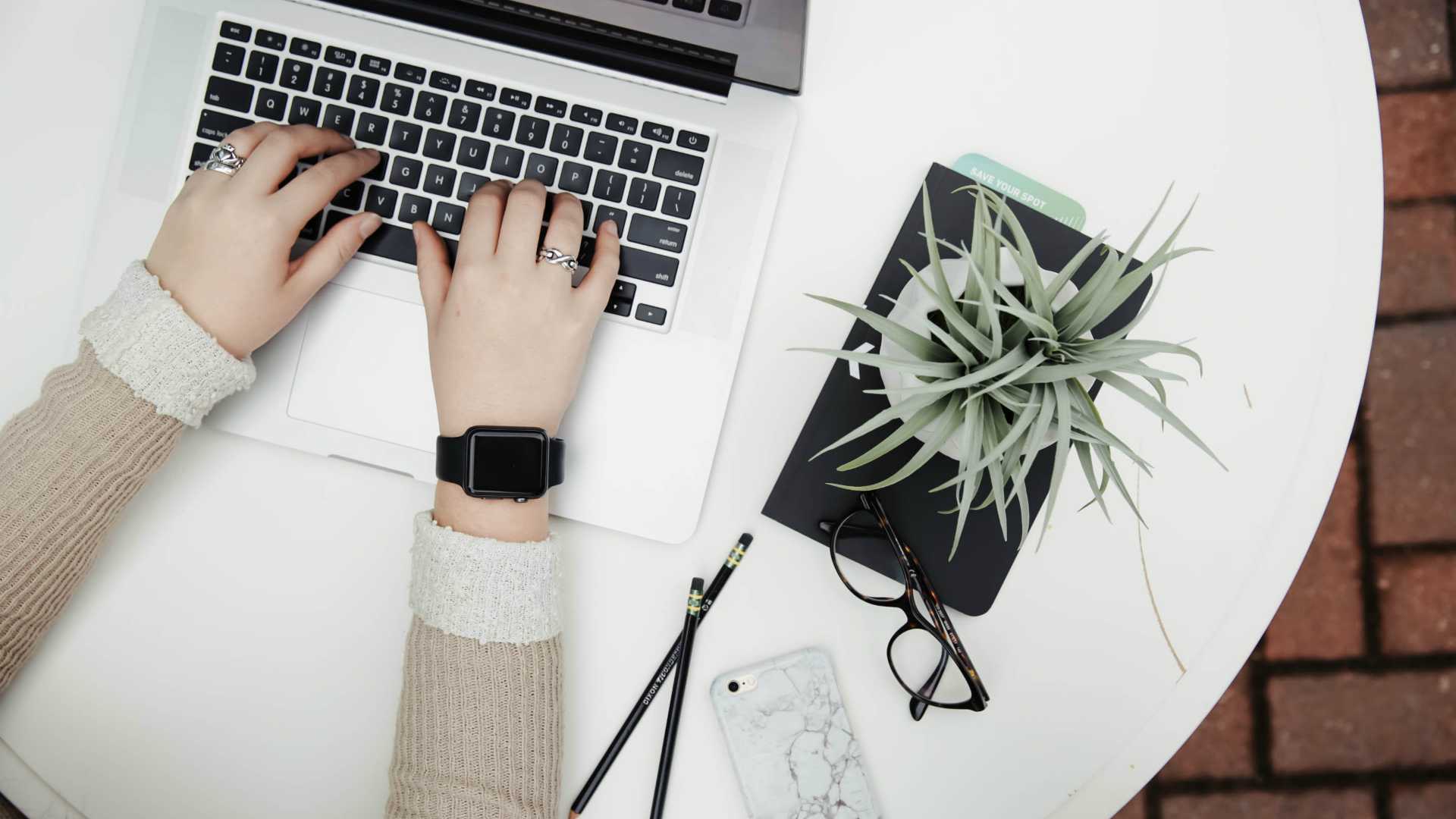 Aerial view of businesswoman working on laptop in home next to notebook and houseplant