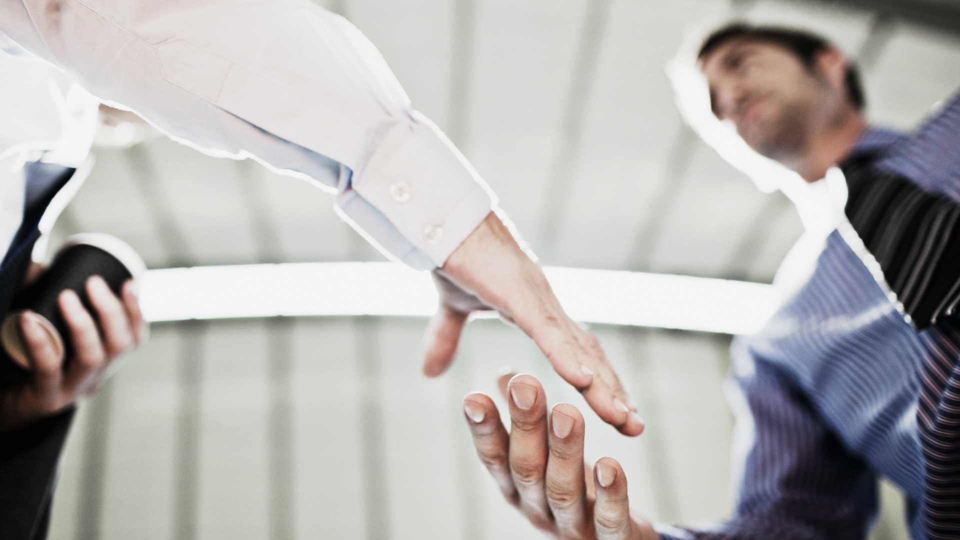 Shot from below. Two businessmen shaking hands in brightly lit office building