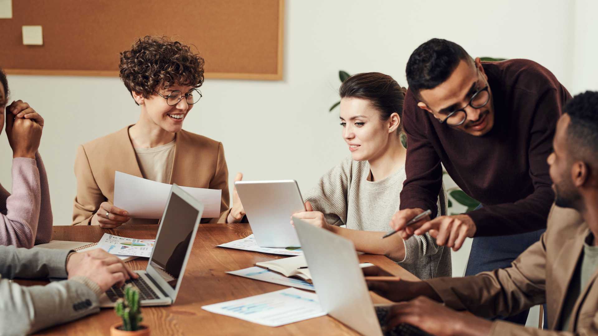 Young, diverse workforce sitting around conference table, collaborating and smiling over team project