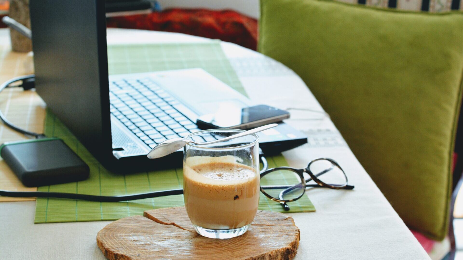 Workspace with green chair, coffee cup and laptop