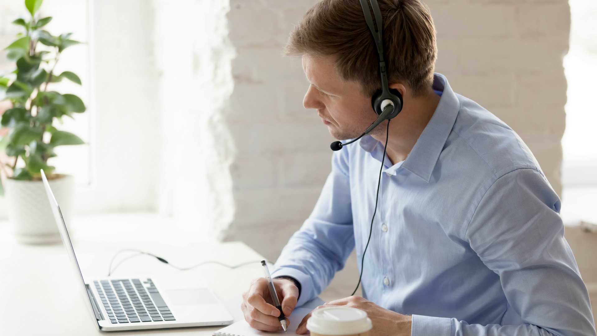 Businessman sitting at workplace improve knowledge use online lessons. Customer service operator wear headset listen client make notes solve problem distantly. Easy learning modern technology concept