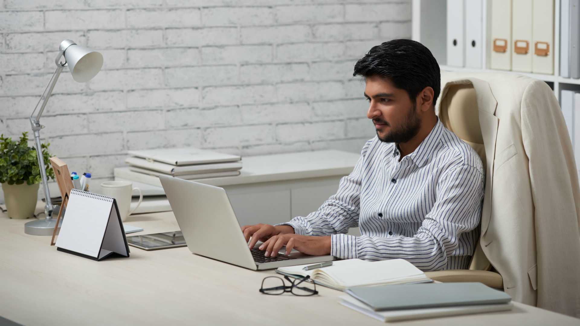 Young Indian businessman working on laptop in his office