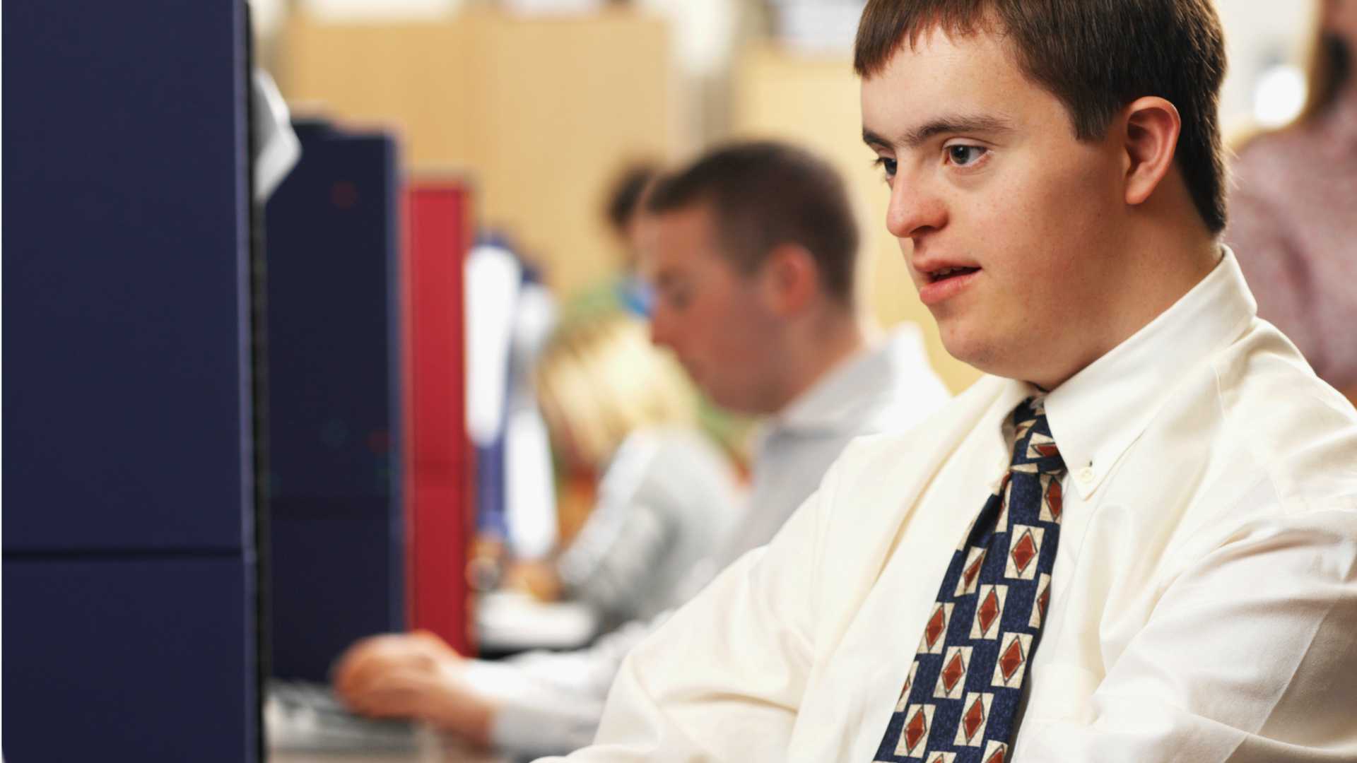 Businessman with intellectual disability working on computer among neurodiverse team