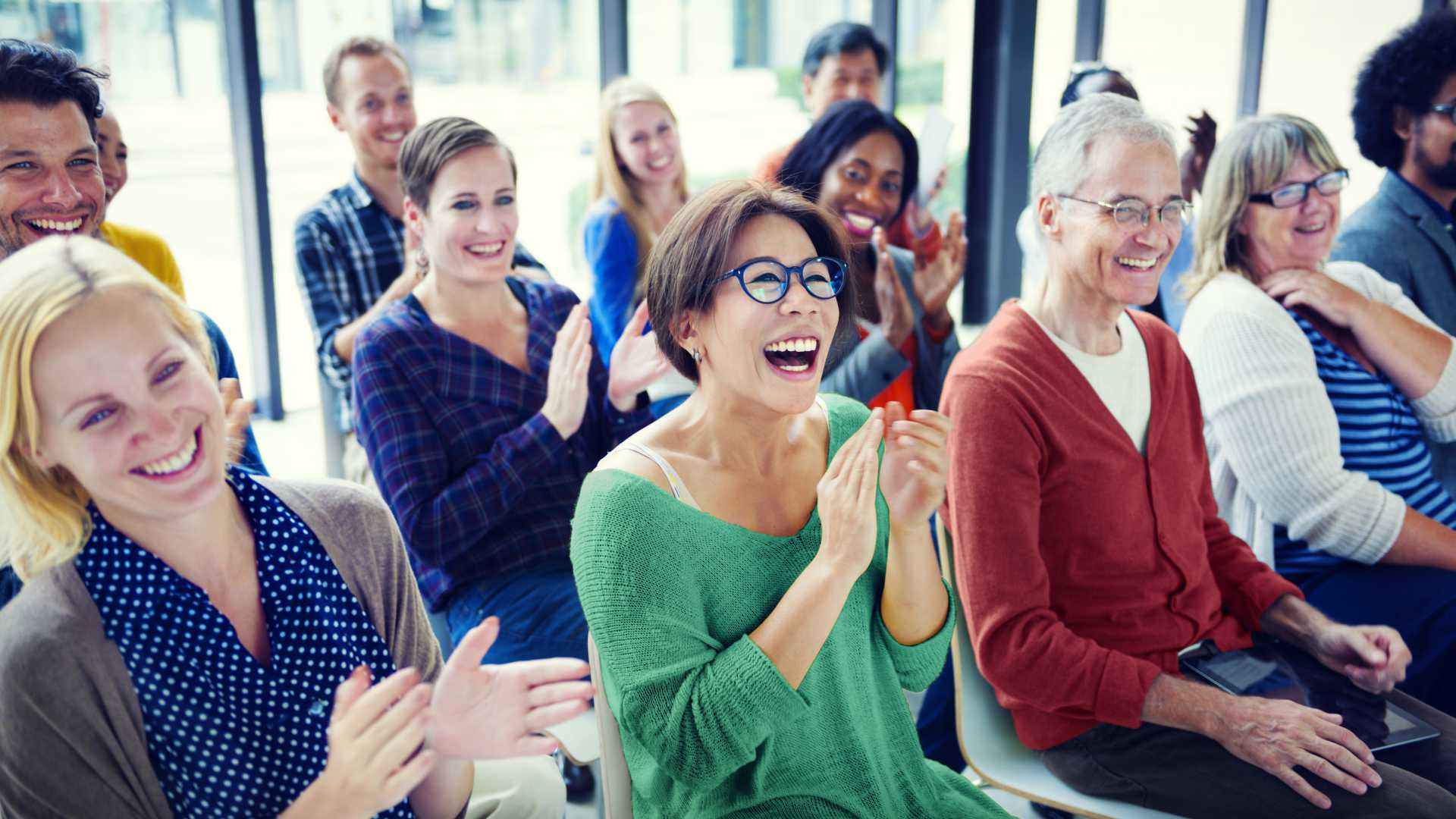 Group of happy, smiling seminar attendees applauding speaker