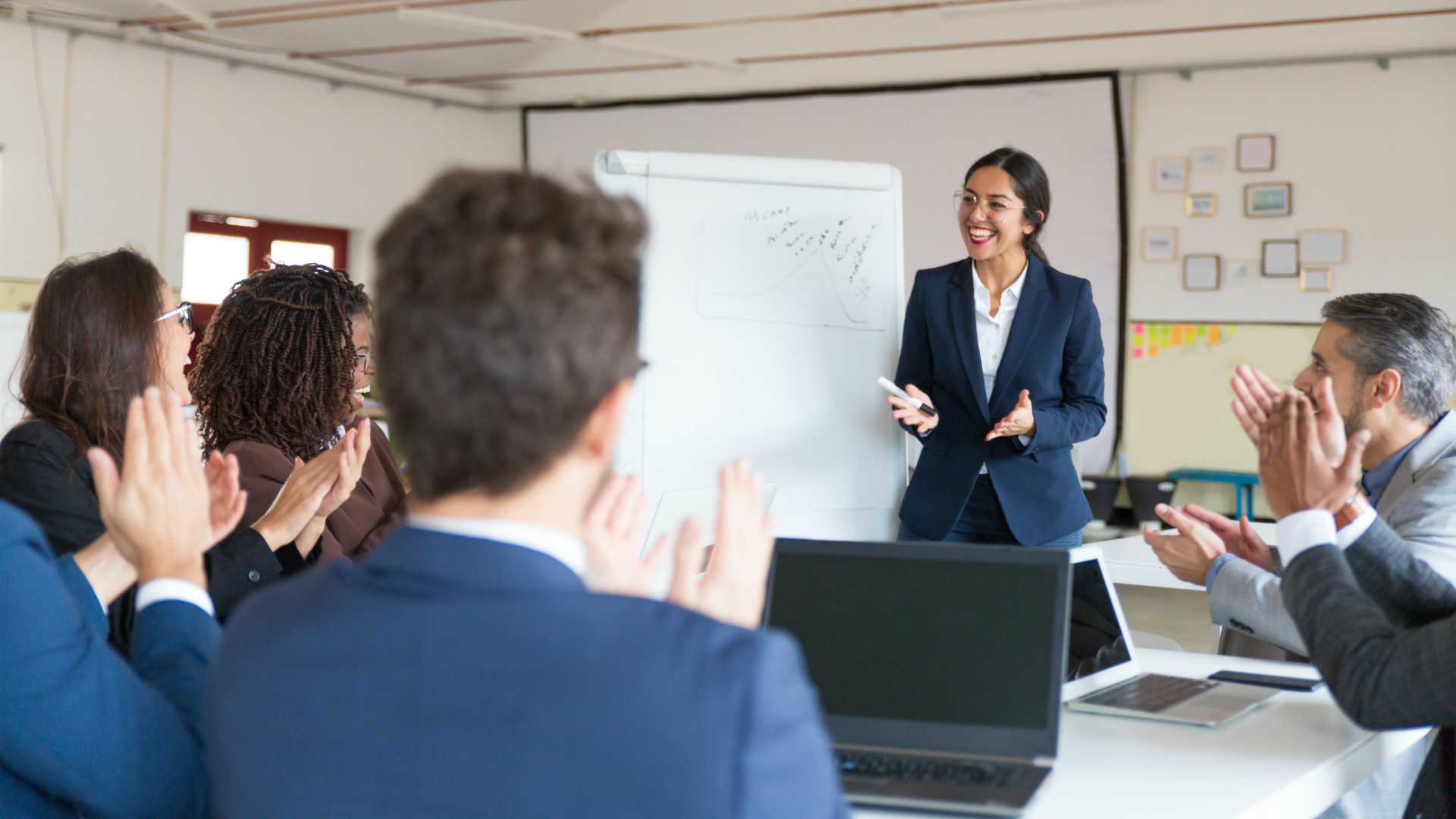 businesswoman receiving applause for great presentation in conference room