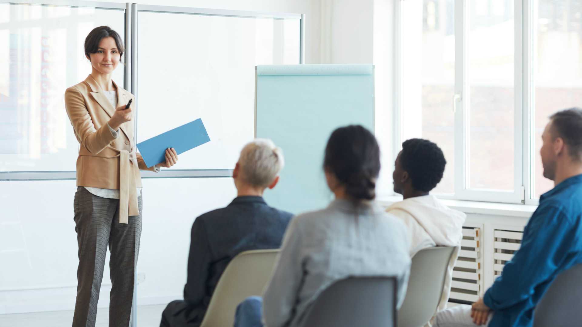 Businesswoman presenting to room of other executives in well-lit conference space