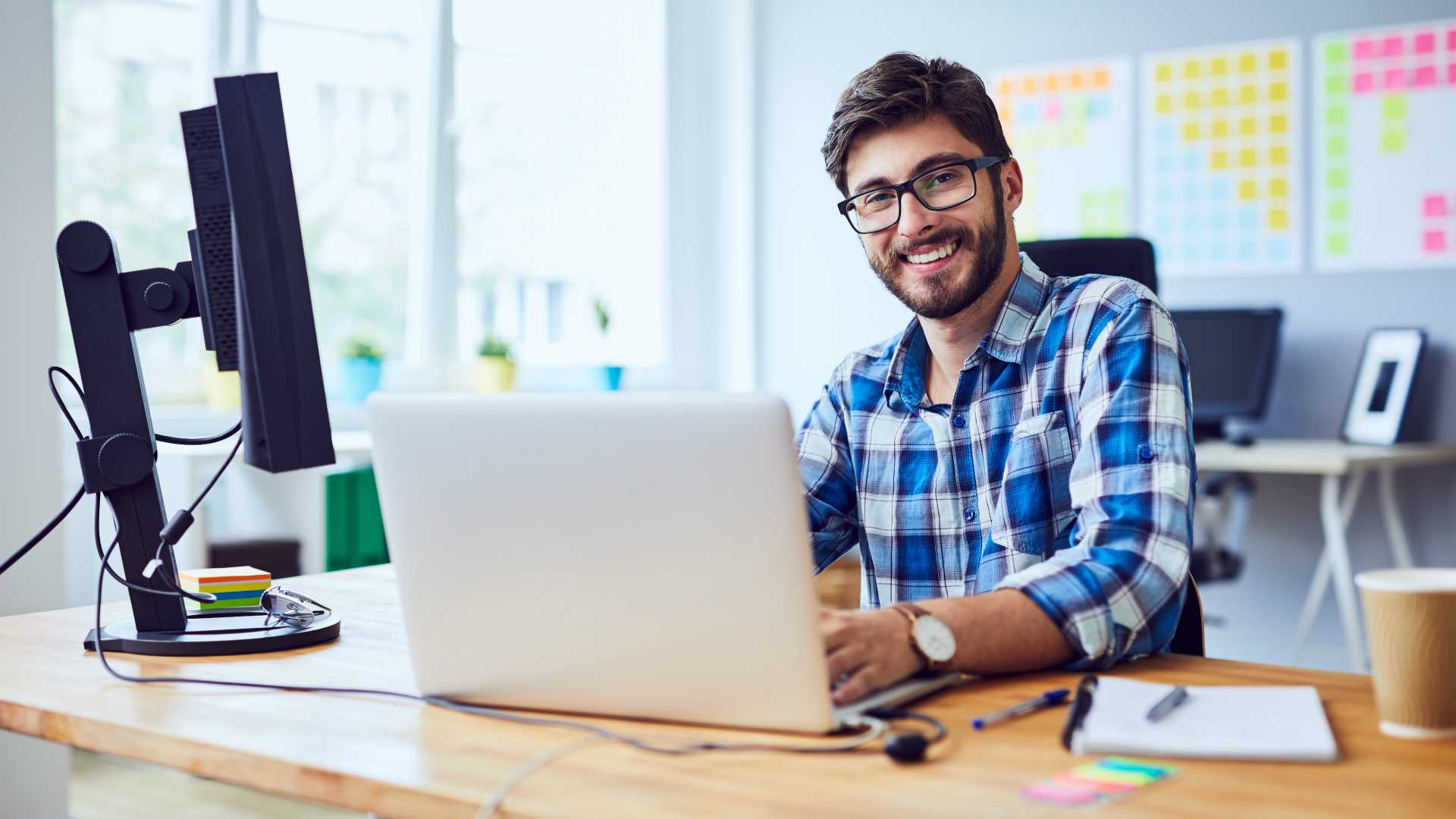 Cheerful young programmer looking at camera while working at his office