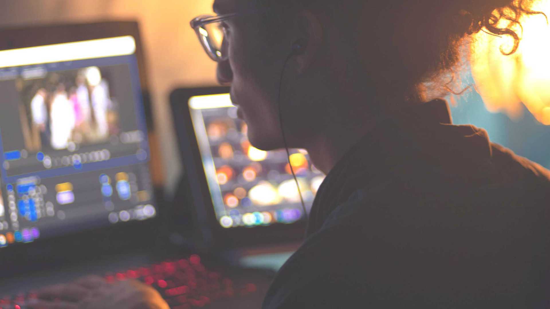 Low lit, over the shoulder shot of employee with curly hair working from home office
