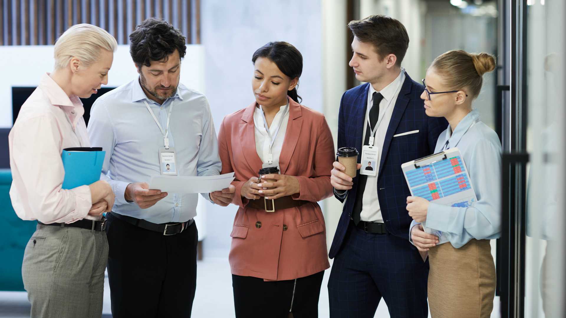 Group of business people standing and discussing documents they preparing for the meeting while standing at office corridor