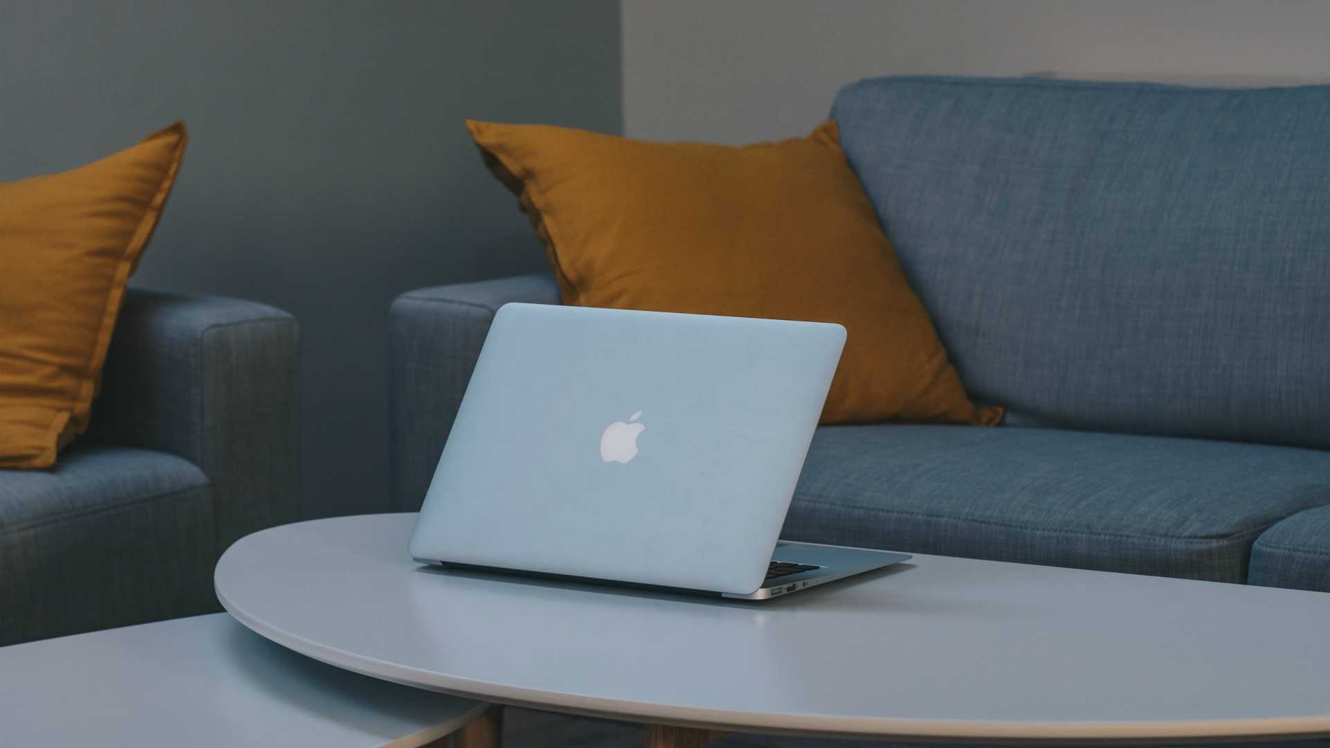 Laptop sitting on coffee table in front of gray couch in modern apartment