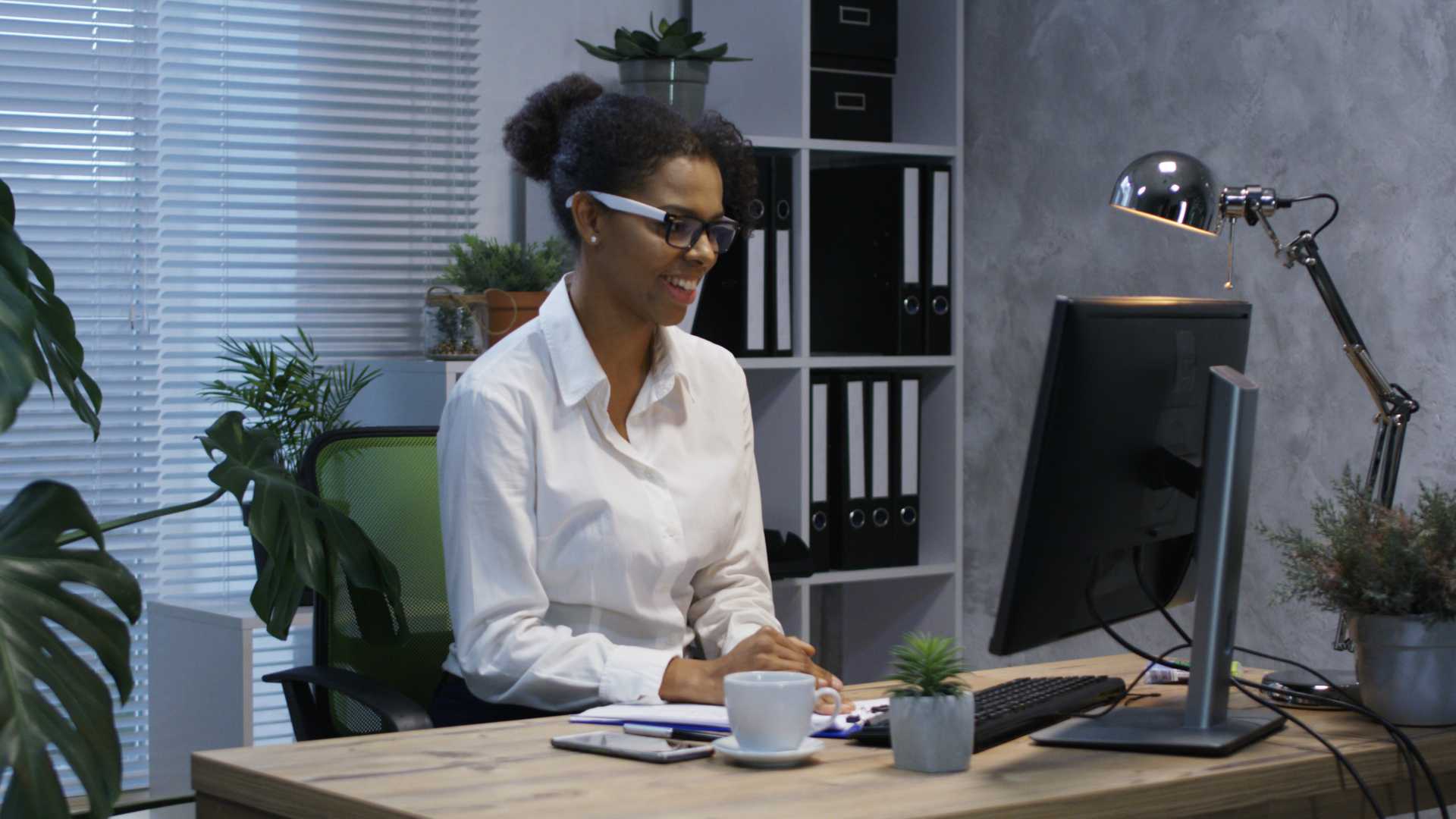 Medium shot of young woman video chatting in office