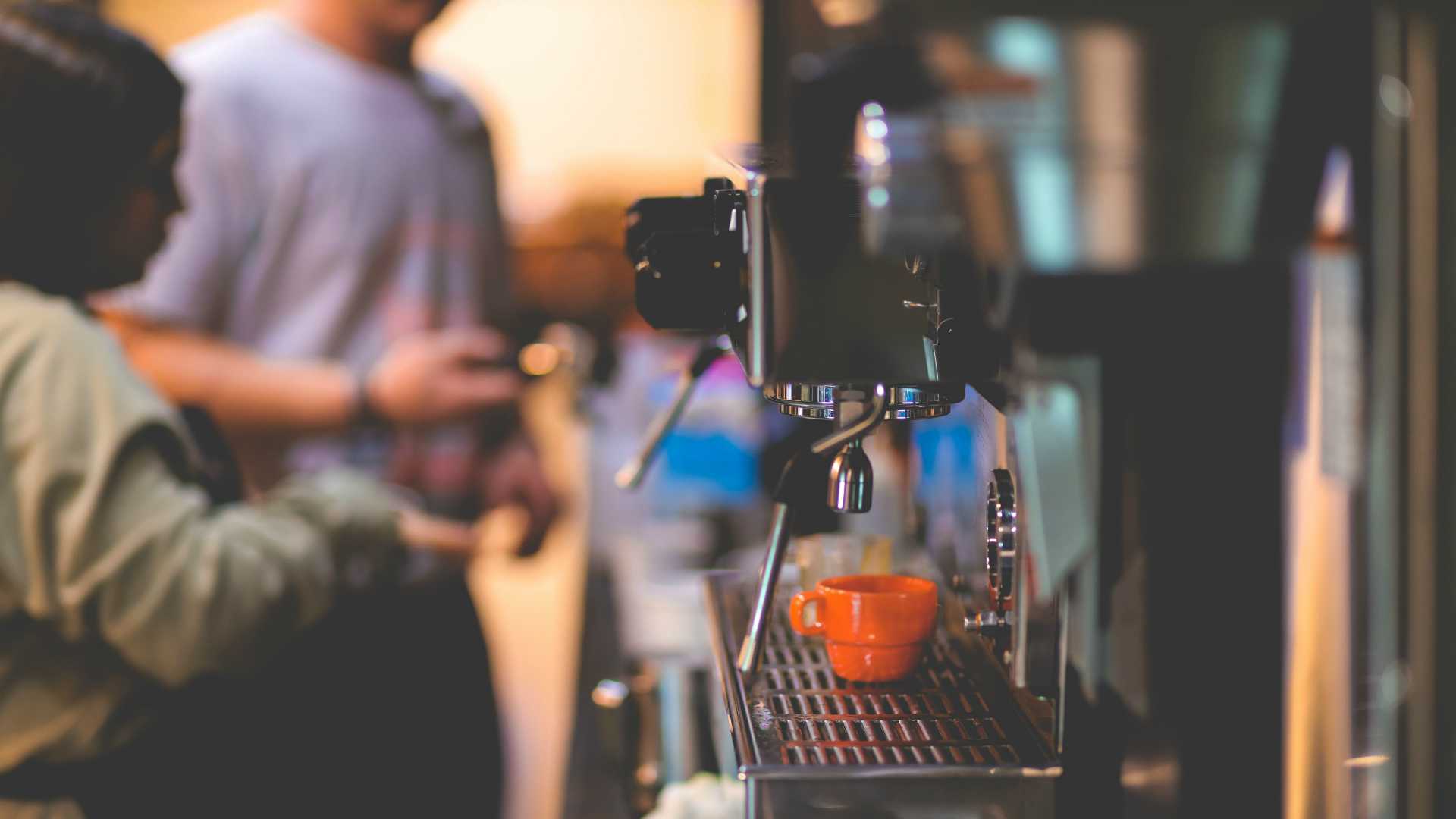 Close up shot of espresso machine and baristas working in background