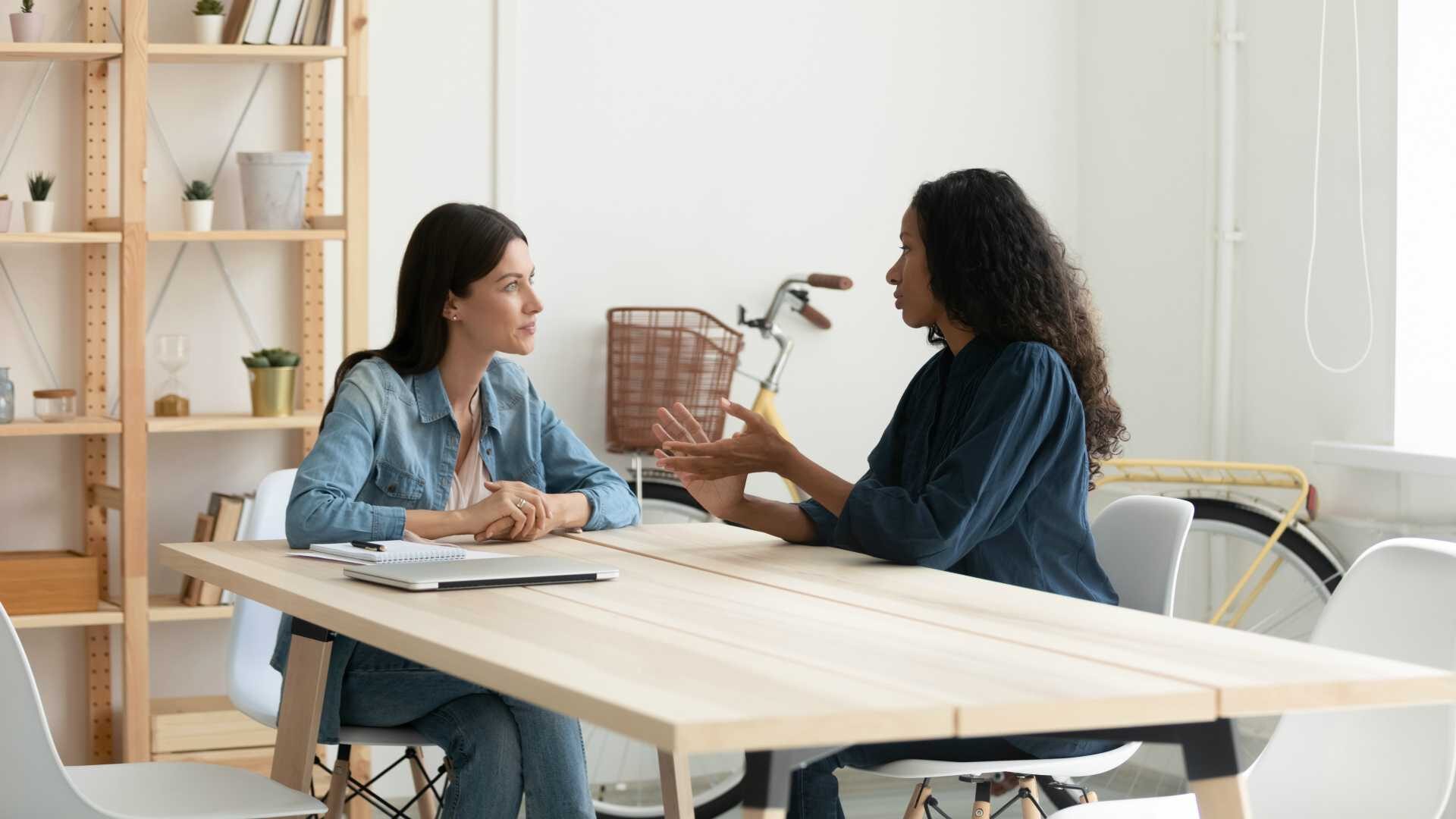 Female leader having disciplinary conversation with female employee in modern office