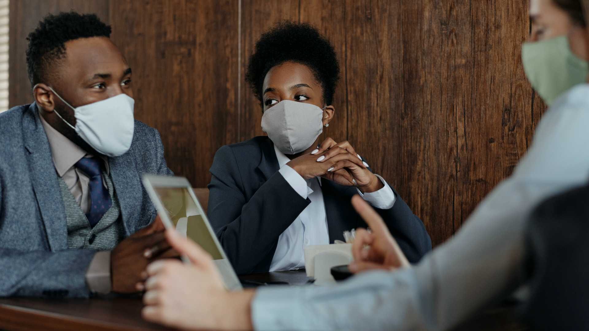 Diverse team holding meeting in conference room with face masks on