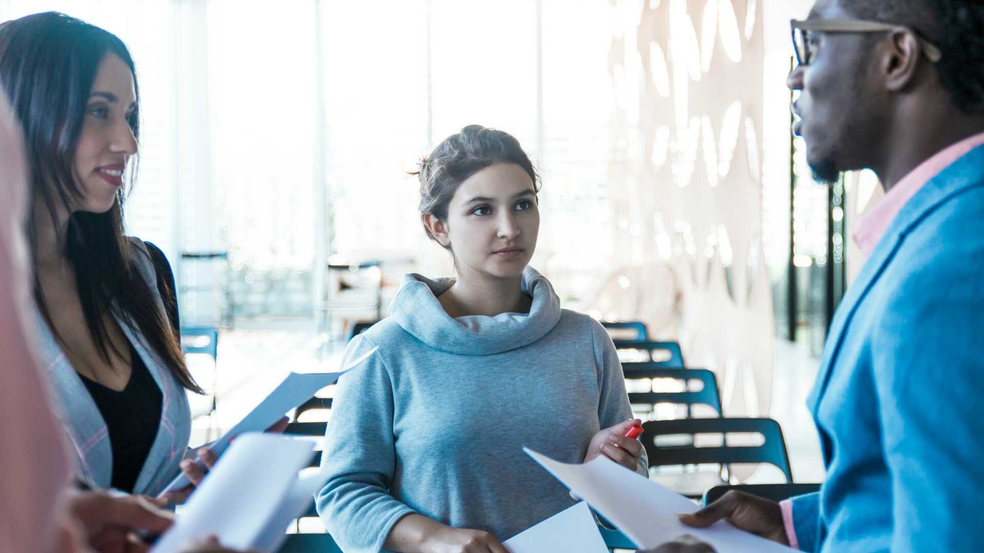 Female mediator at center of photo with one female colleague to left and one male colleague to right facilitating conversation about workplace conflict