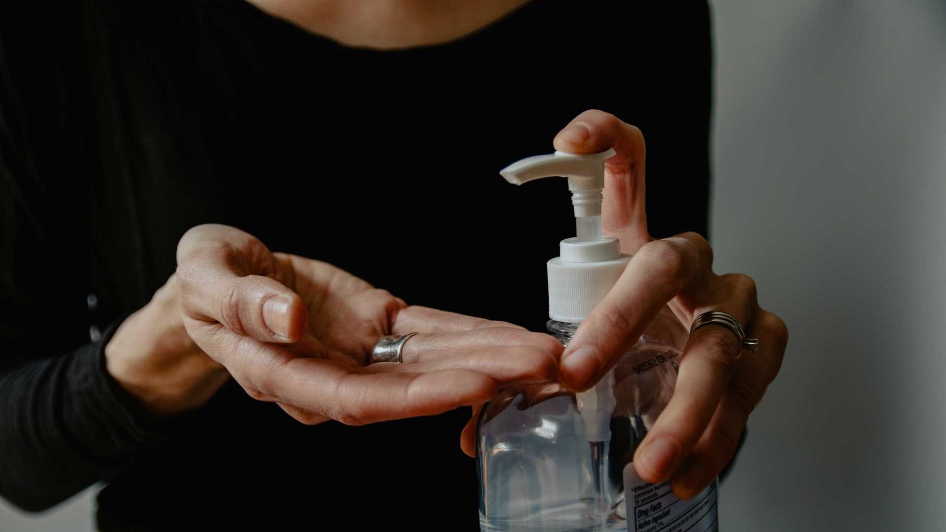 Dimly lit shot of woman putting hand sanitizer in palm