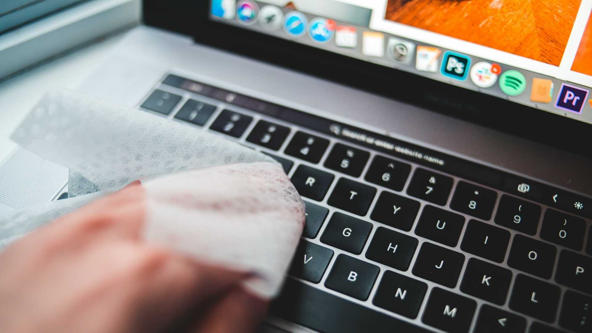 Close up shot of person wiping down laptop keyboard