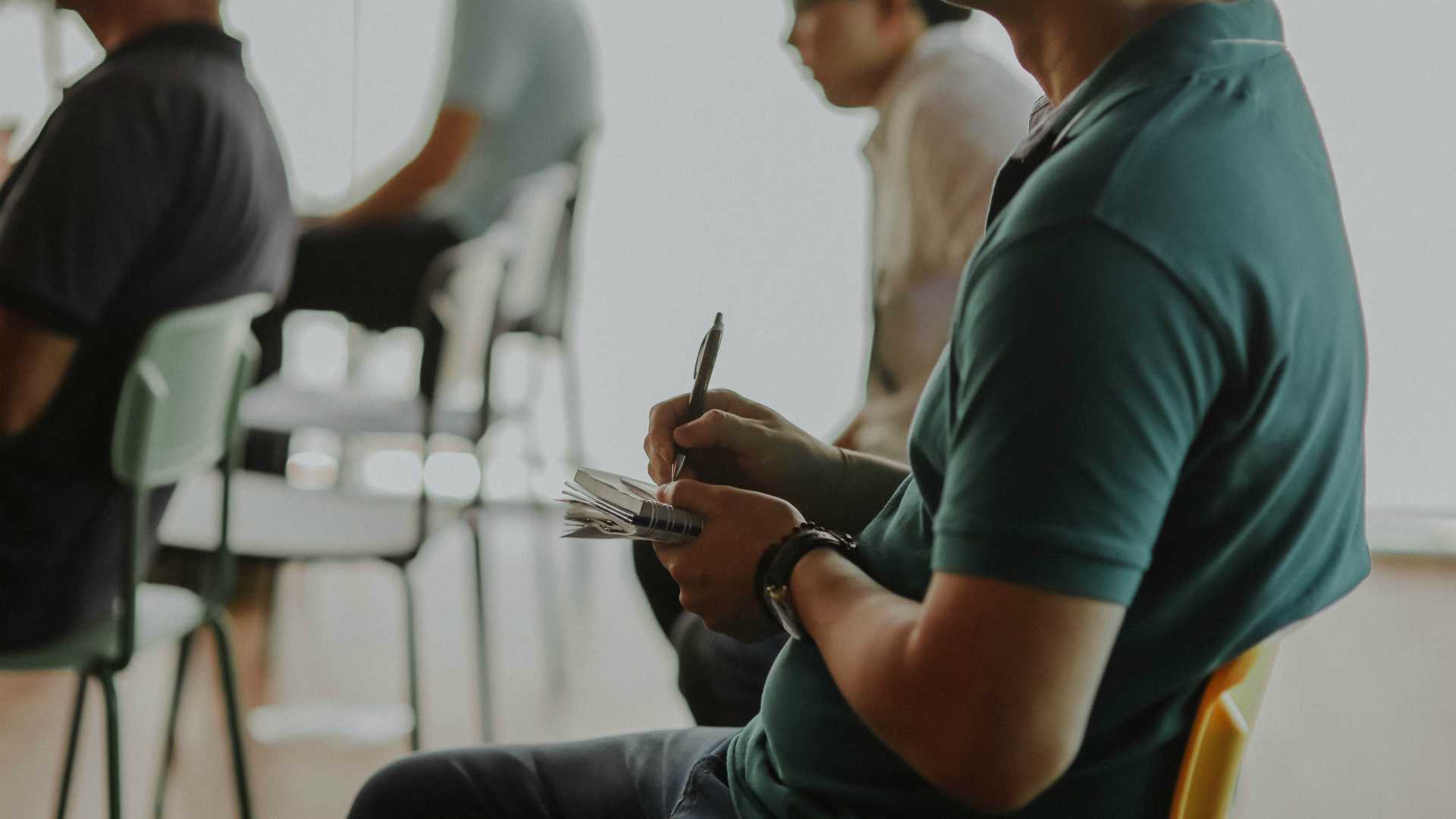 Business man taking notes with other students in backgroundin training course