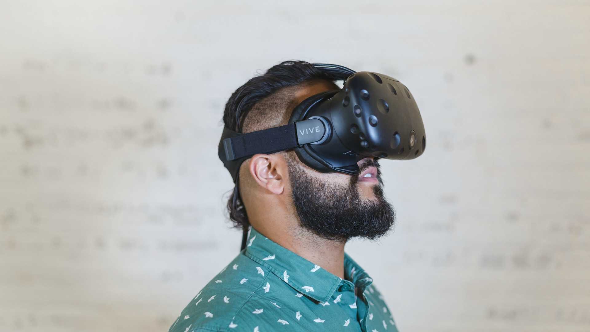 Man wearing virtual reality goggles in front of whiteboard covered in notes