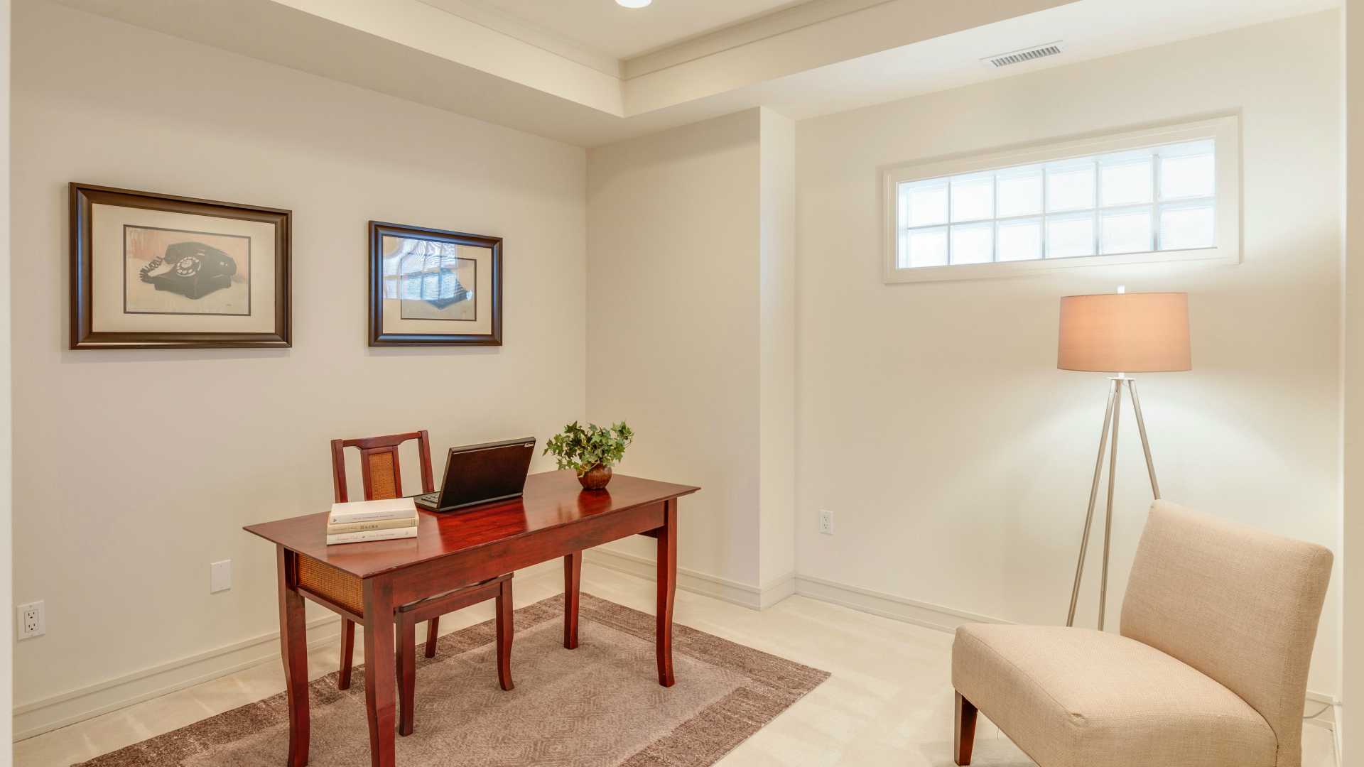 Tidy home office with lamp and chair in right corner and desk with laptop on opposite side of room