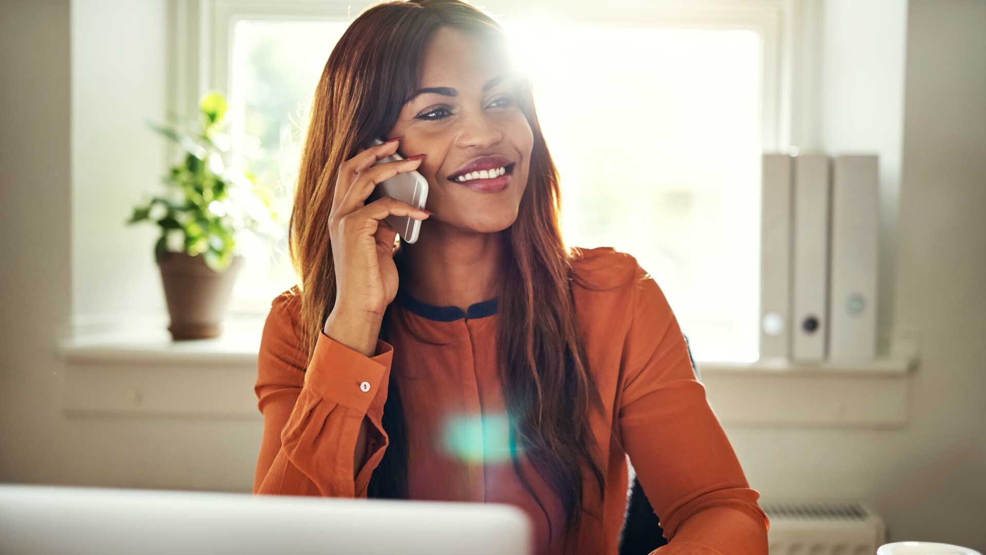 Businesswoman smiling and talking on telephone in home