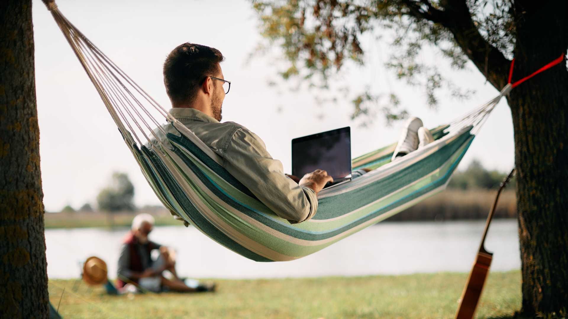 a learner looks at streaming training content on a laptop while lounging on a hammock