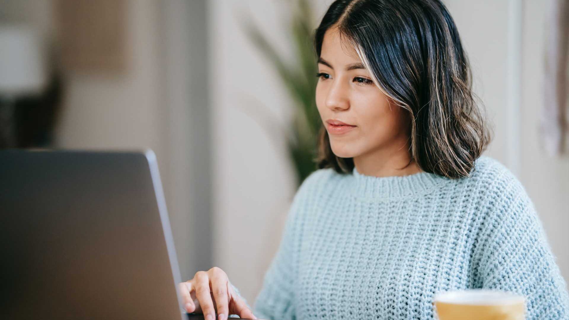 A woman sits at a desk in front of a laptop.
