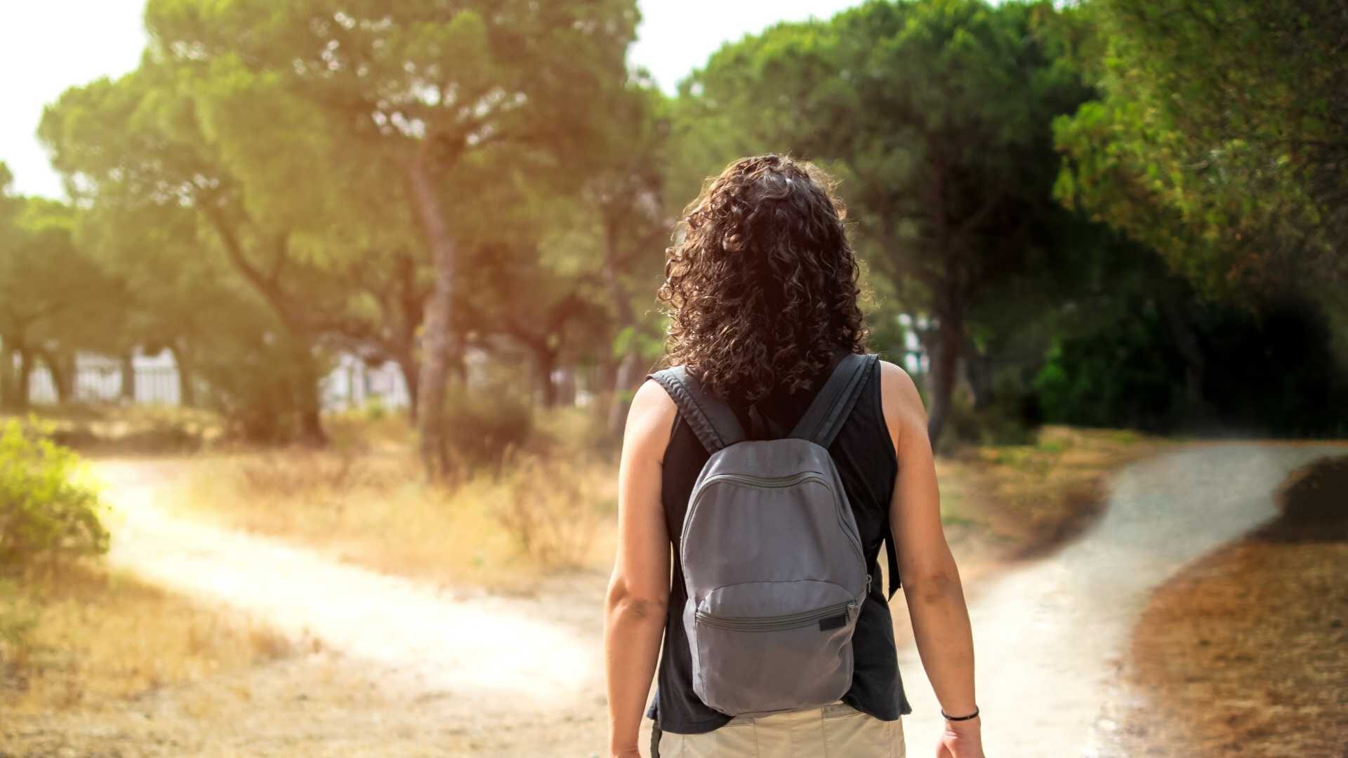 A woman stands in front of two paths outdoors.