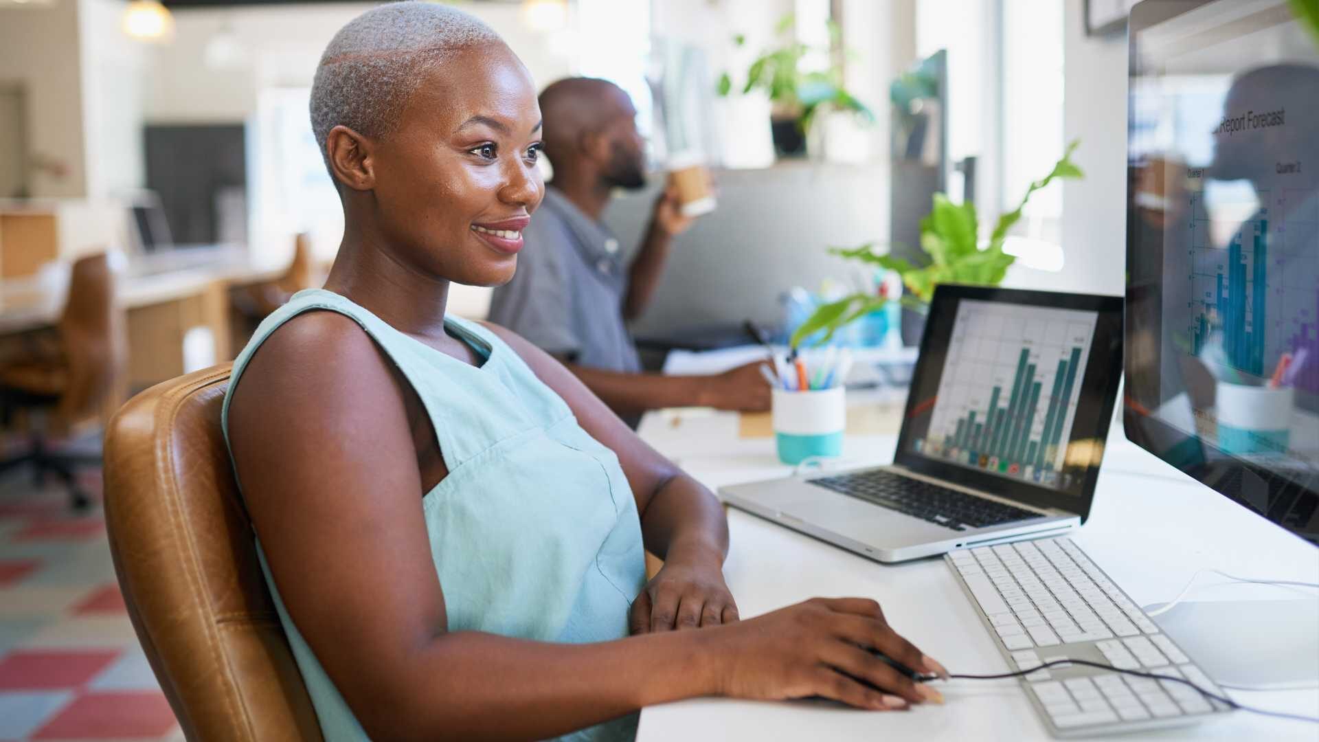 A woman works on a financial forecast report in open plan office
