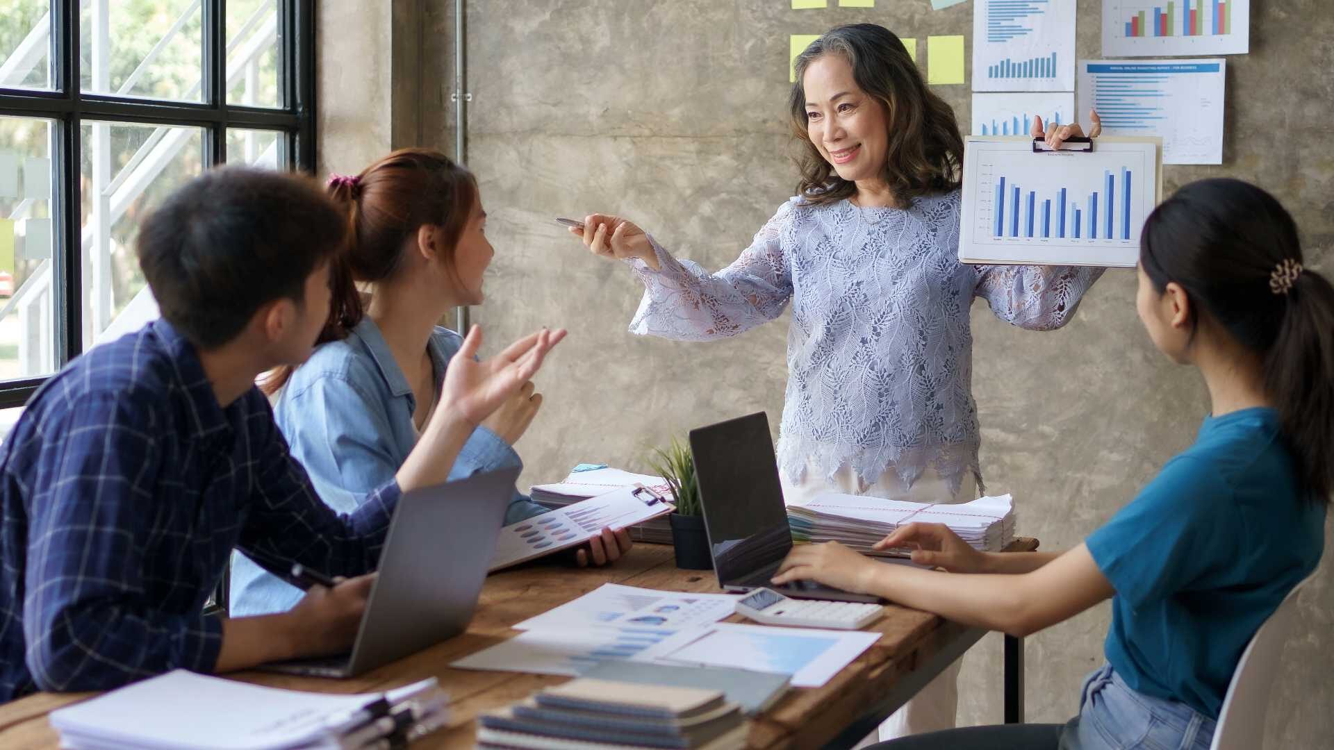 A team of business people are sitting together at office looking at charts and graphs.
