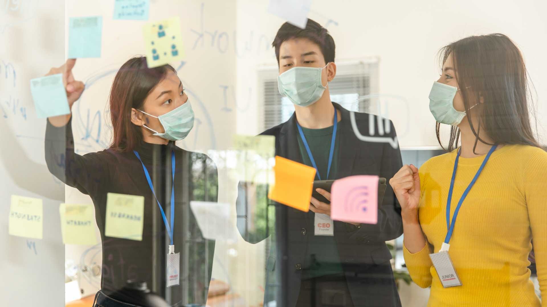 three young business people look at an array of notes they've stuck to a window