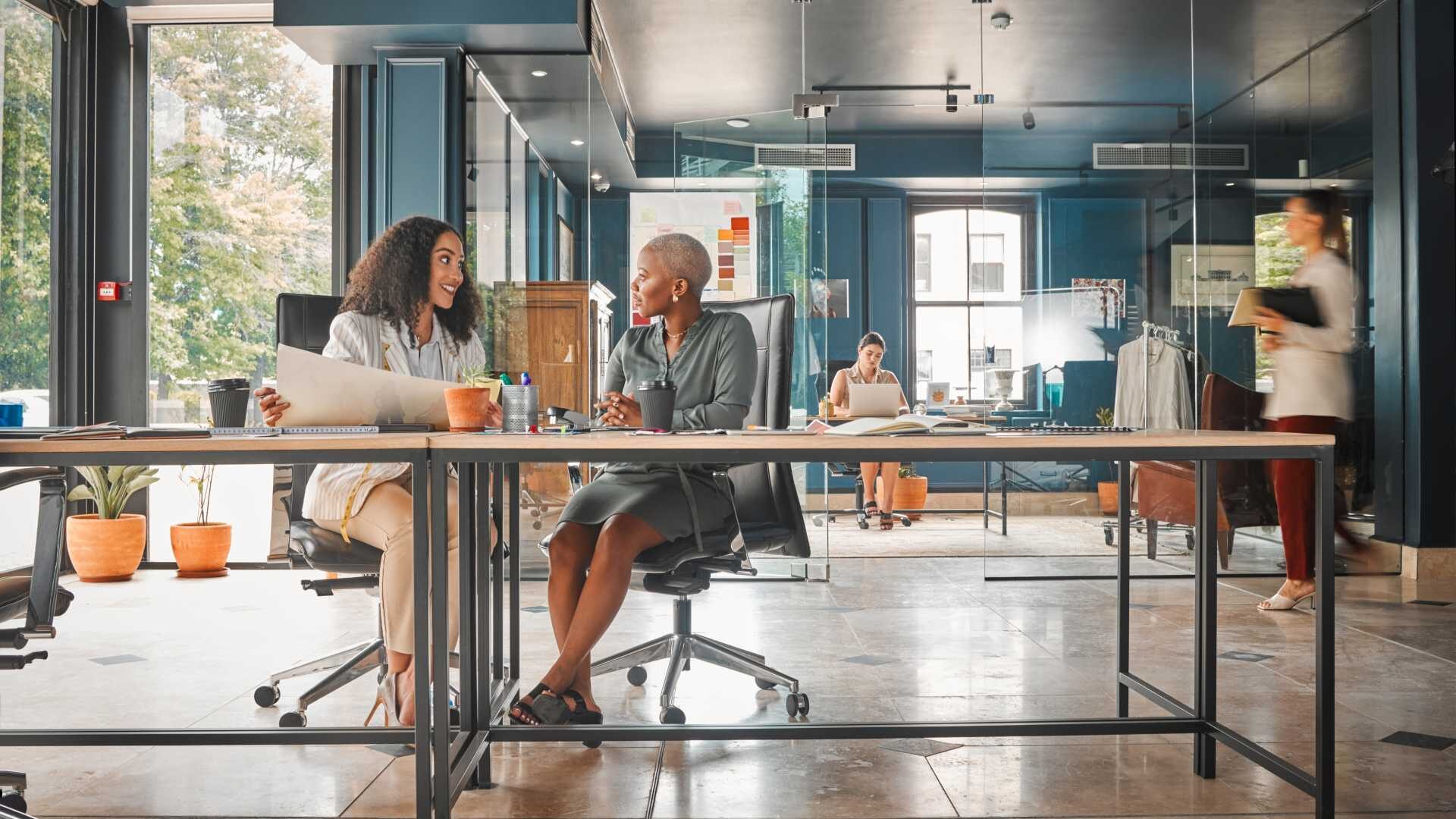 Two business people are having a discussion at a table in an office.