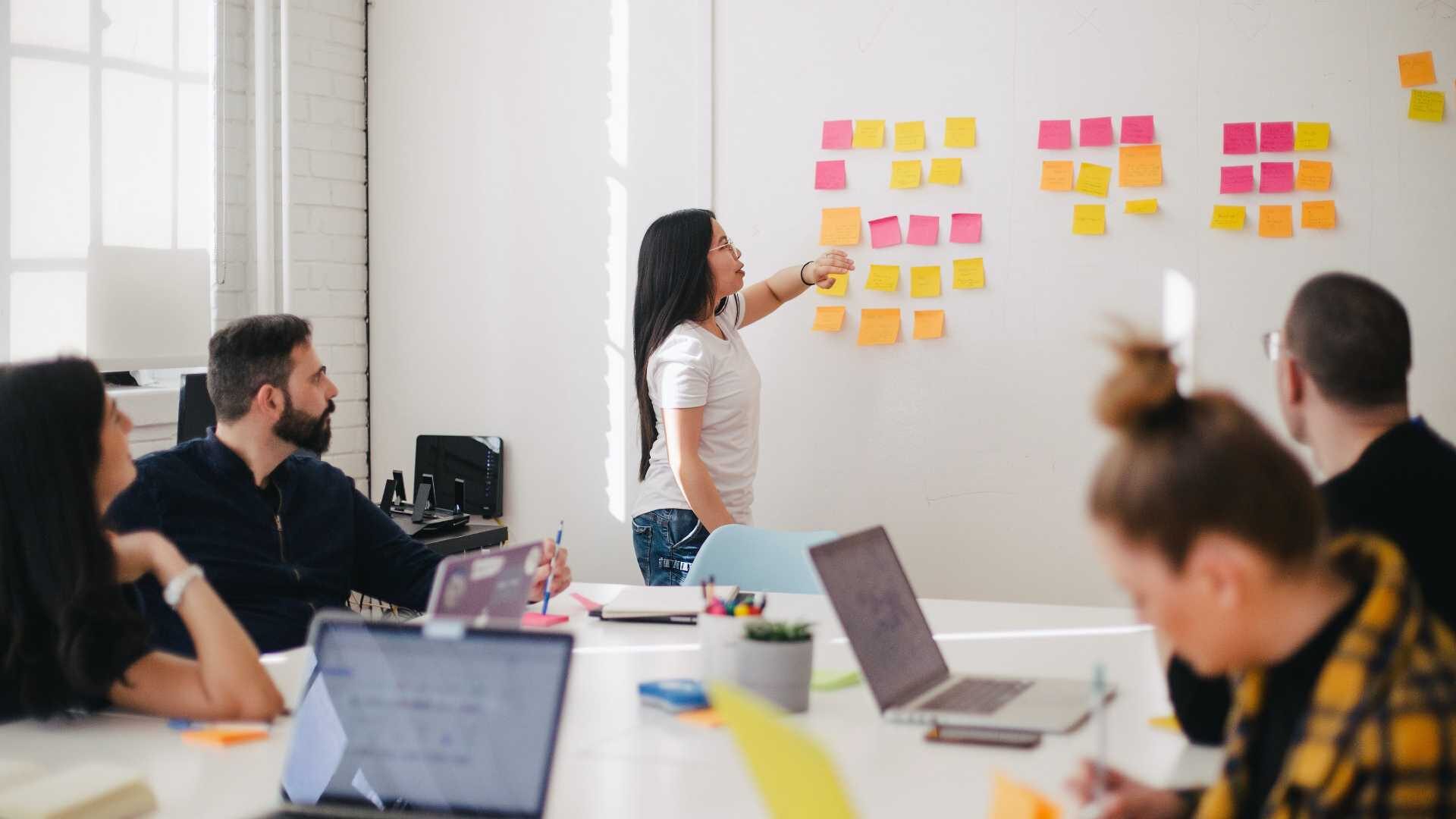 A group of coworkers strategizes about tech skills shortages using post-it notes.