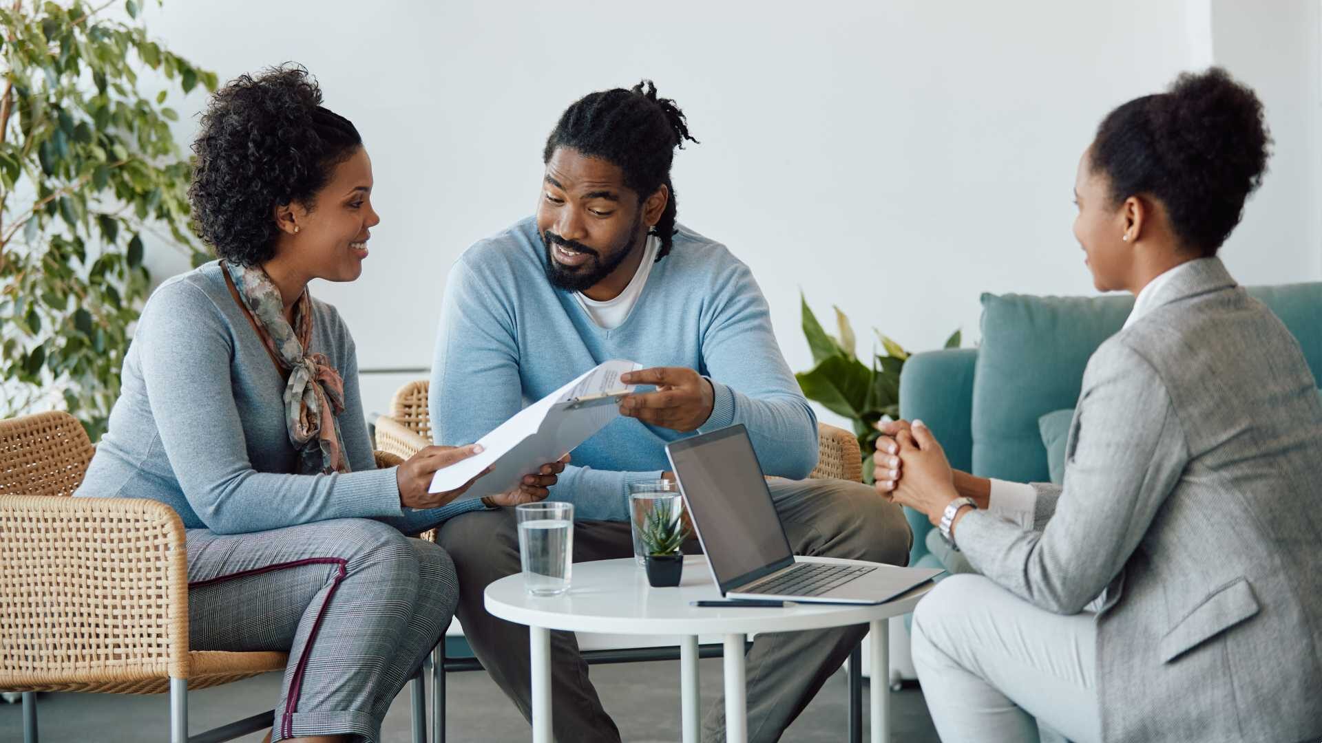 Three people sit around a table looking at paperwork