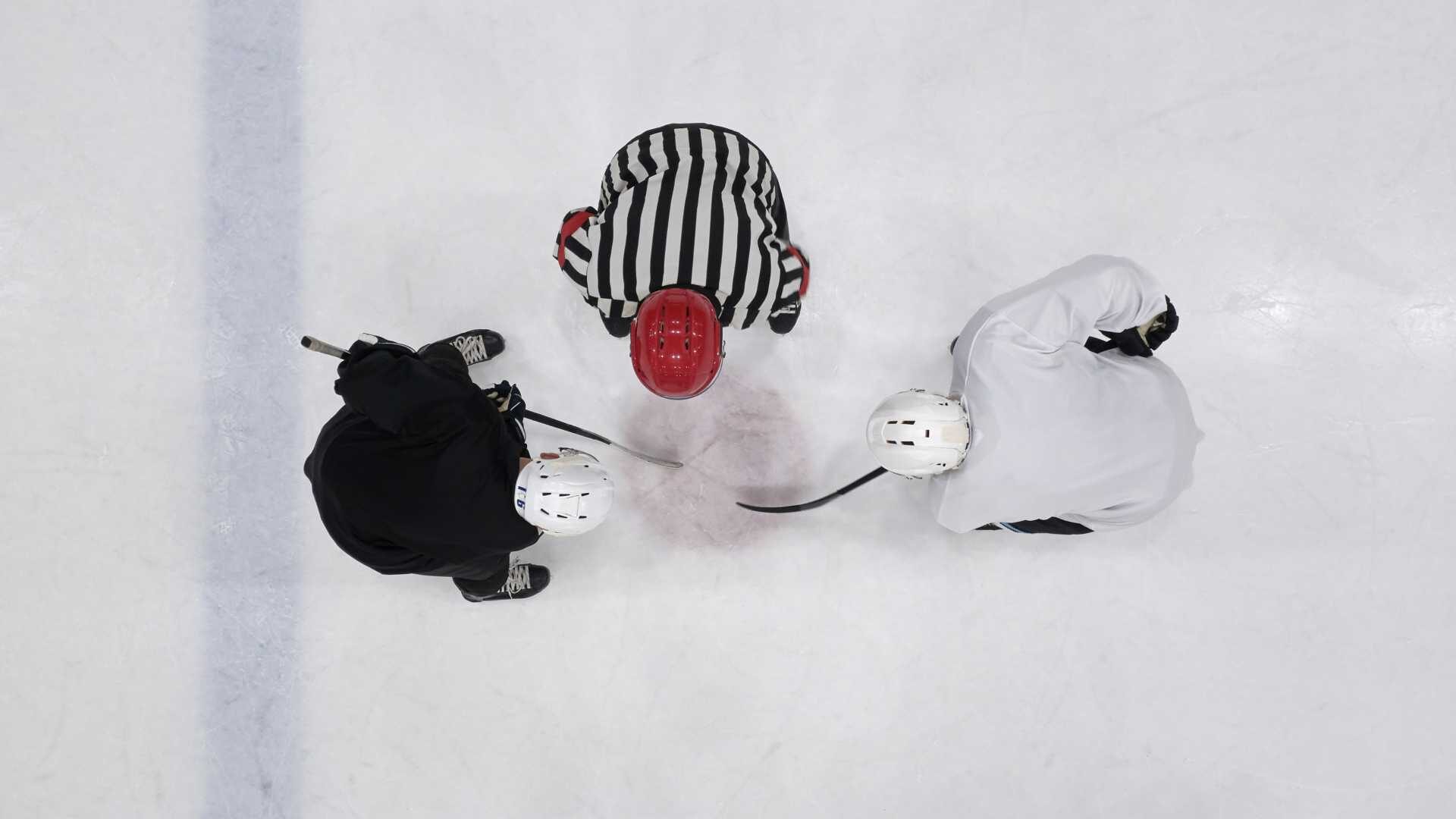Two hockey players face off as the referee is about to drop the puck